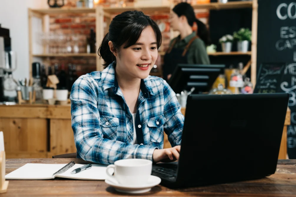 Woman using a laptop for work in a coffee shop