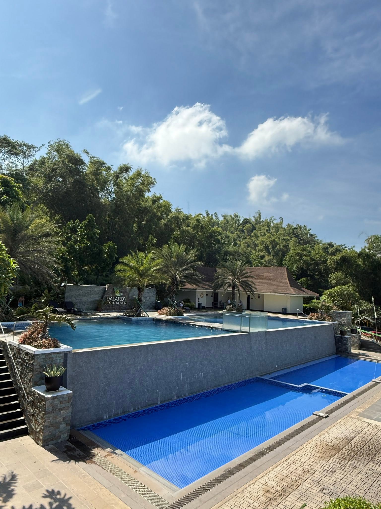 Dalaroy Beach Resort in Ternate with a multi-level pool, surrounded by lush greenery and clear blue skies.