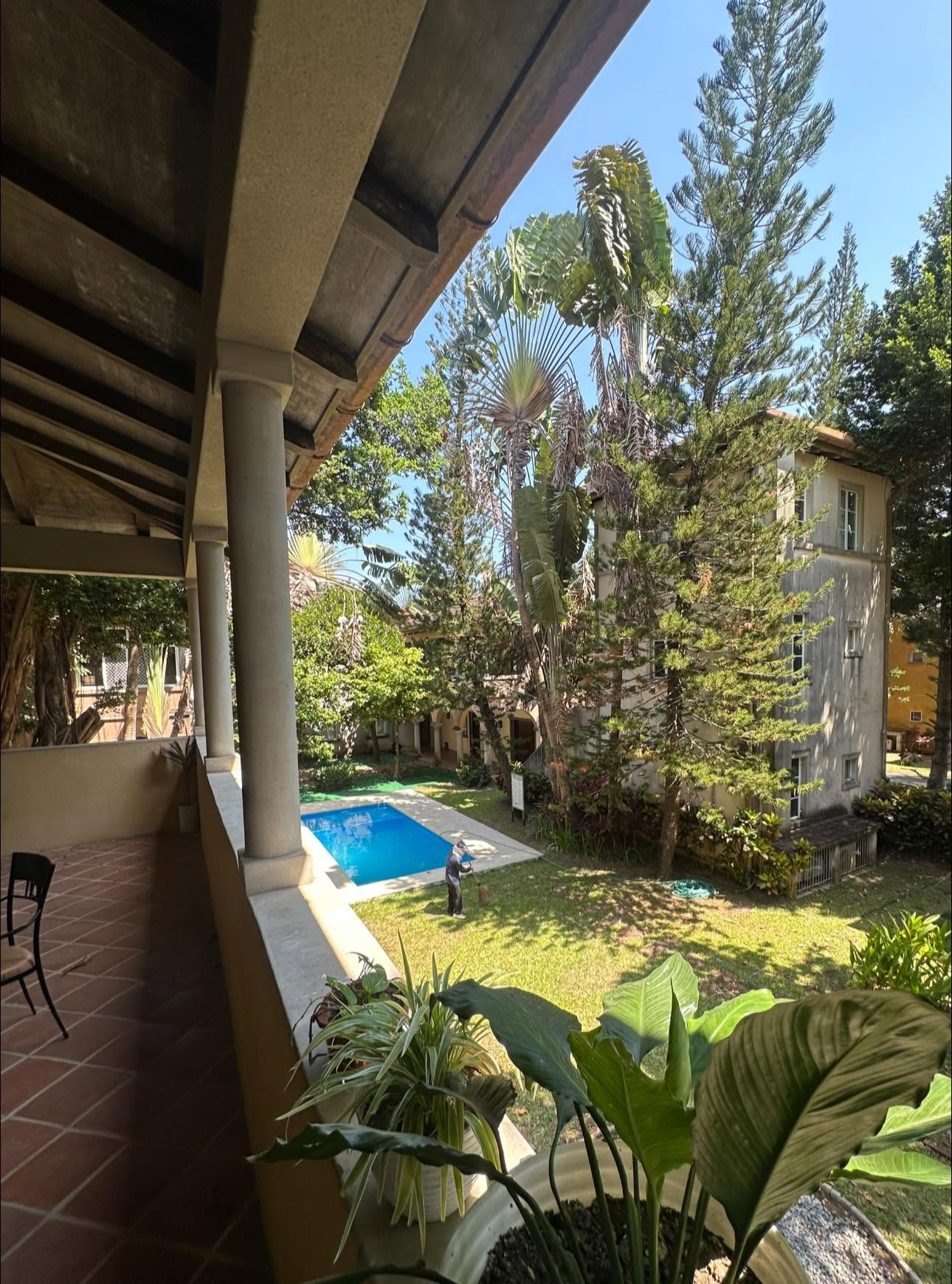 View from a balcony overlooking a garden and pool at Caylabne Bay Resort & Marina, Ternate, surrounded by lush trees.