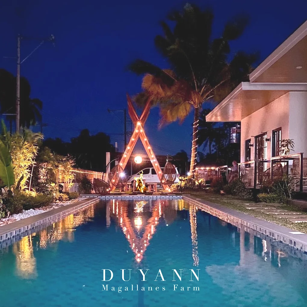 Night view of Duyann Magallanes Farm with a lit poolside and palm trees in Magallanes, Cavite.