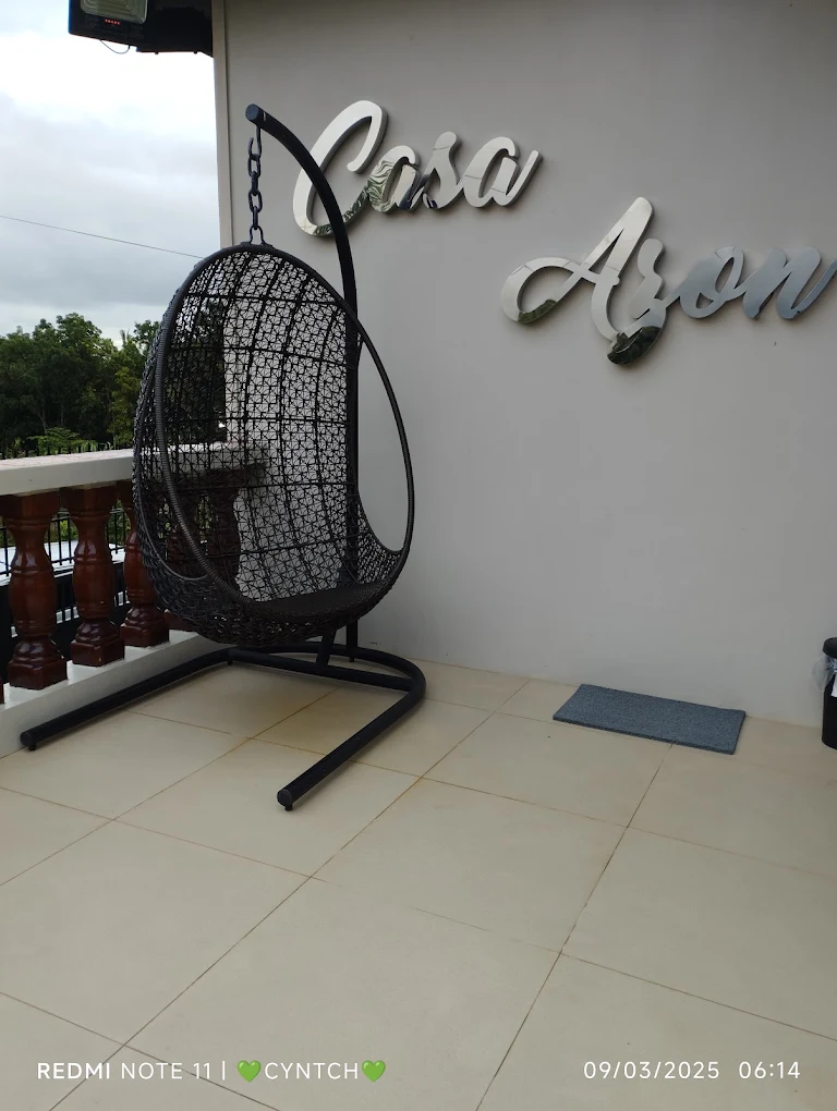 Hanging chair on Casa Azon's terrace in Alfonso, Cavite, with a view of greenery.