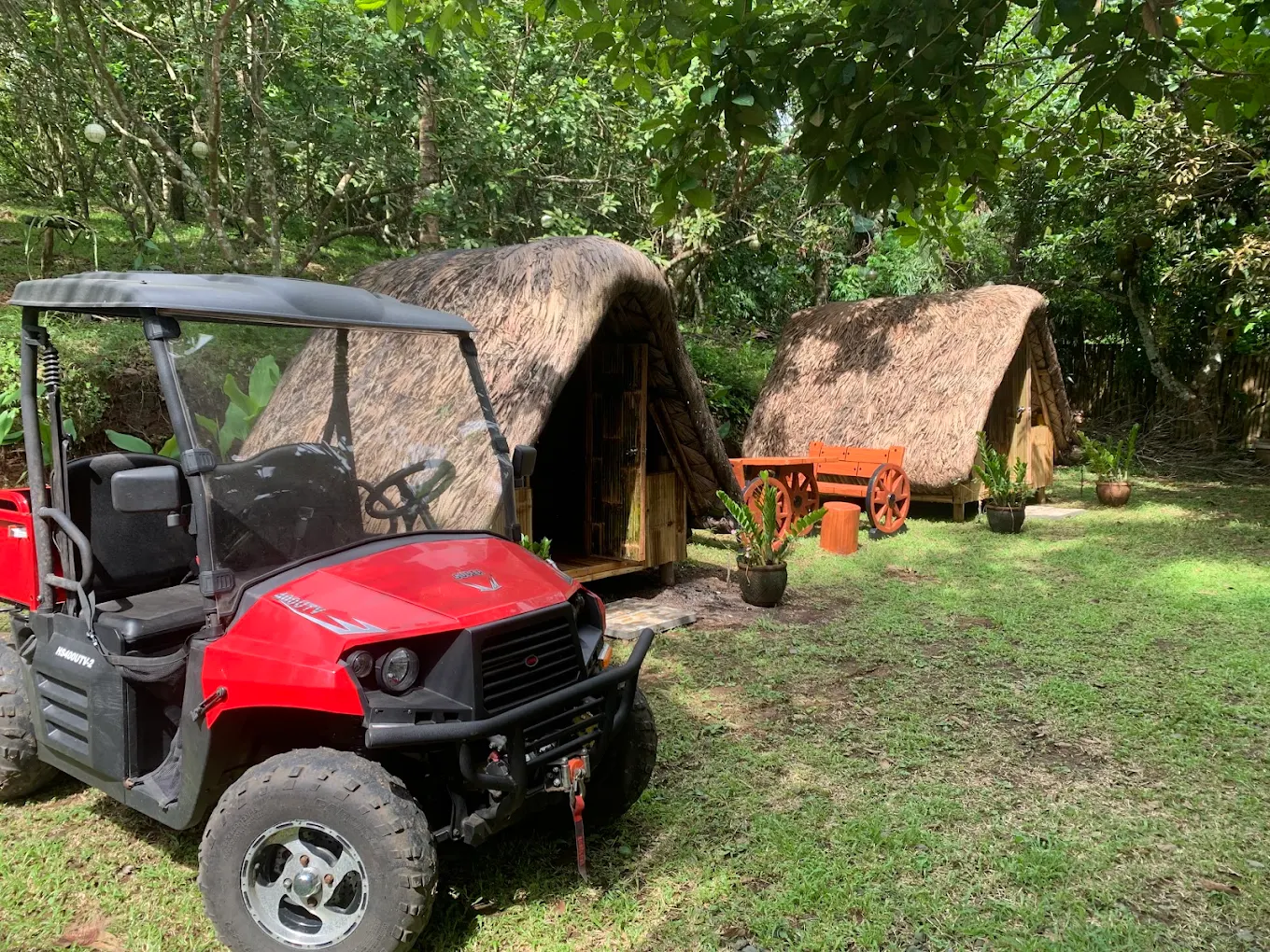 Red ATV parked near rustic huts at Balai Khulith Farm & Resort, Indang, surrounded by lush greenery.