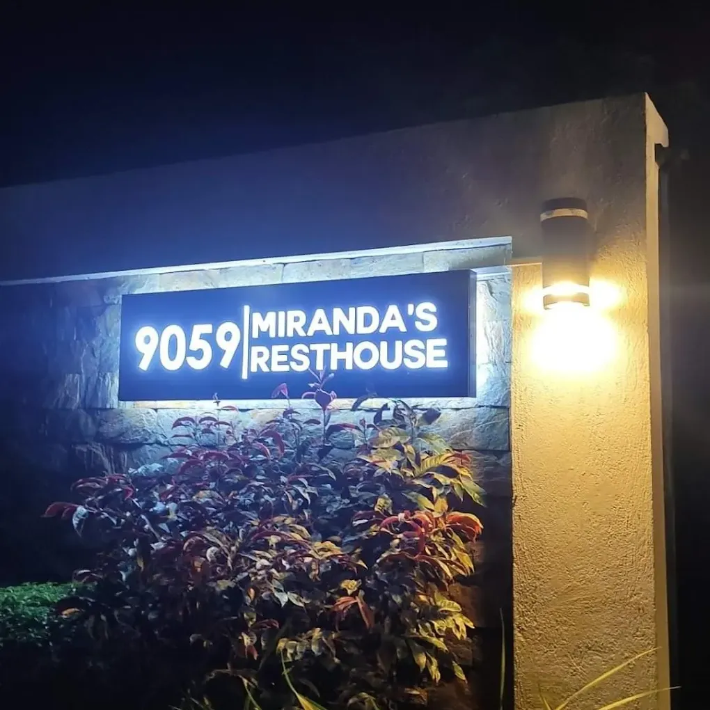 Miranda's Resthouse illuminated sign with plants at night in Alfonso, Cavite.