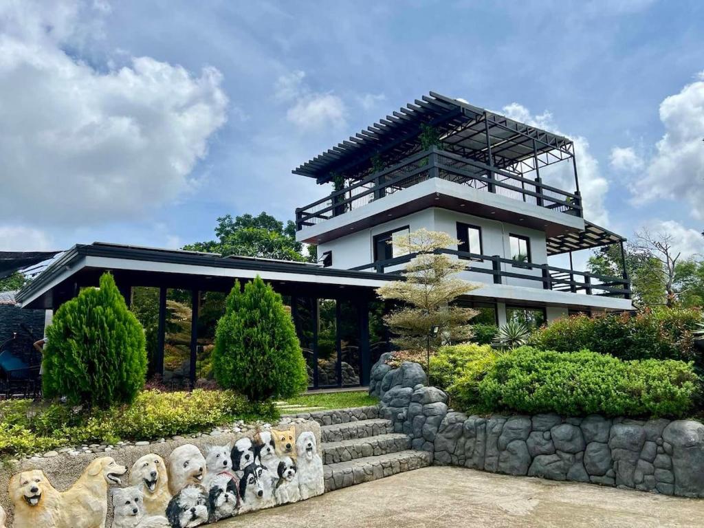 Modern building with lush greenery at Alfonso Hotel and Farm, featuring stone sculptures and a clear blue sky.
