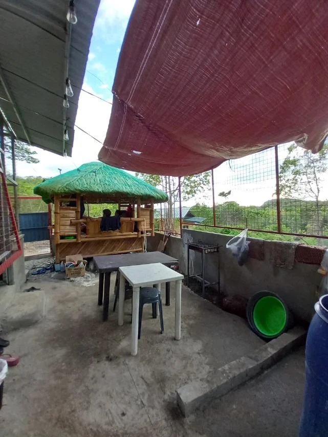 Outdoor seating area with tables and a bamboo hut at MeLi MaRt Transient House in General Mariano Alvarez.