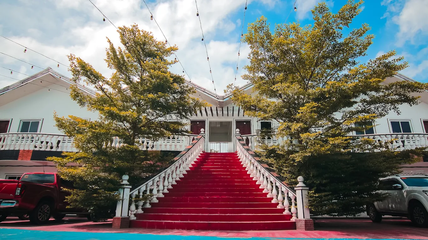 Red carpeted stairs leading to Villa Marca Resort Hotel entrance, surrounded by trees in Silang, Cavite.