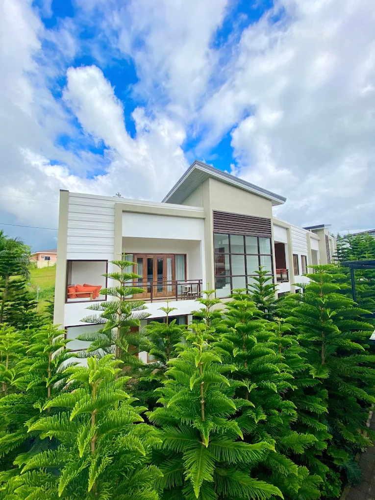 Modern white building surrounded by lush greenery at Farm Hilss Garden Bed and Breakfast, Silang.