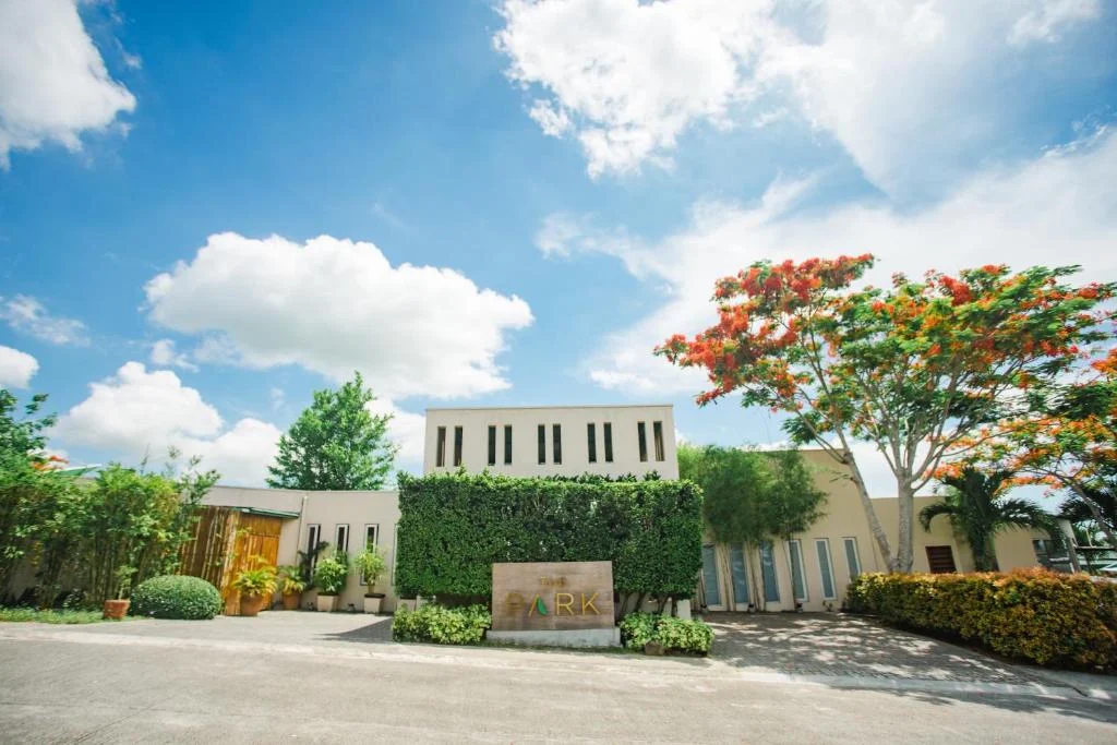 Modern building with lush greenery and vibrant trees at The Park Silang, Silang, Cavite under a bright blue sky.