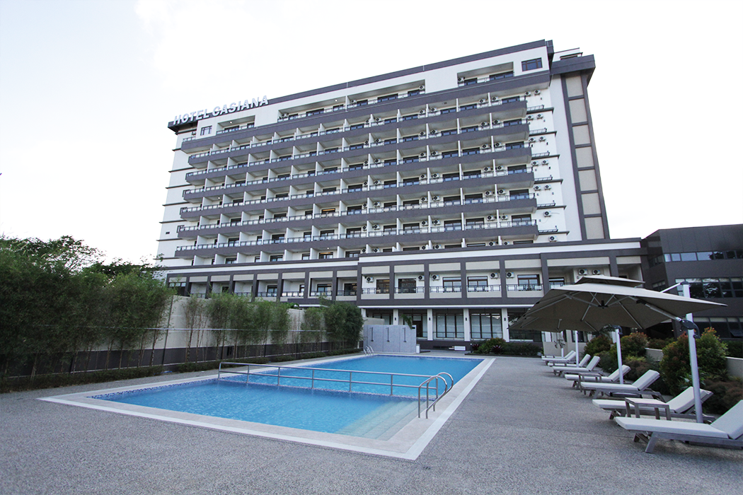 Hotel Casiana in Tagaytay with a modern facade and outdoor swimming pool surrounded by lounge chairs and umbrellas.