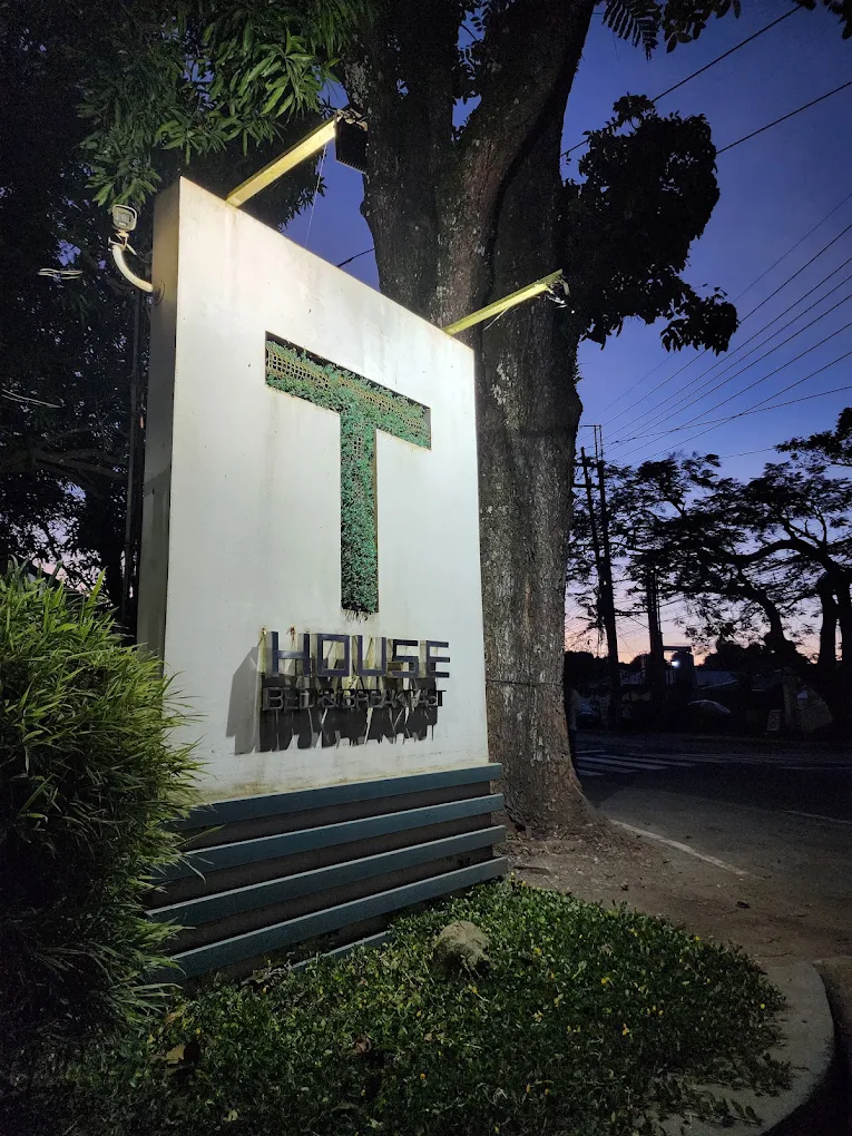 T House Tagaytay sign illuminated at dusk, surrounded by trees and greenery in Tagaytay.