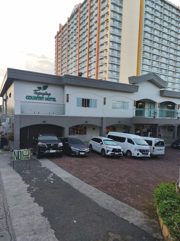 Tagaytay Country Hotel entrance with parked cars and a tall building in the background, Tagaytay City.