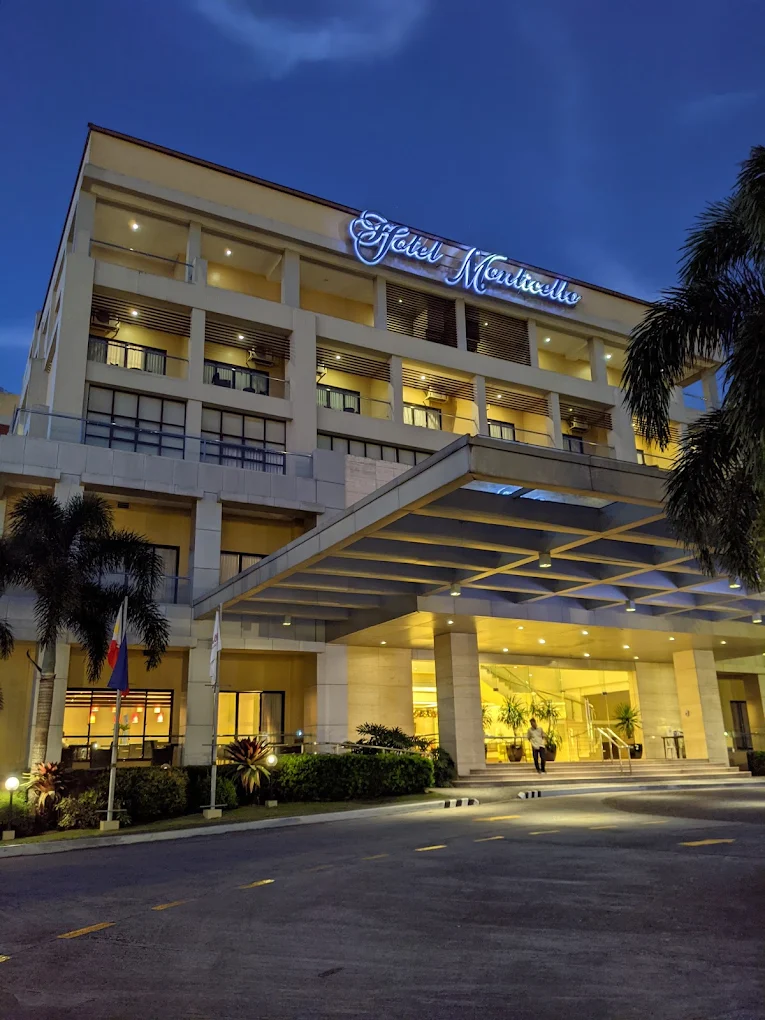 Hotel Monticello facade at night with illuminated signage, palm trees, and entrance in Tagaytay, Cavite.