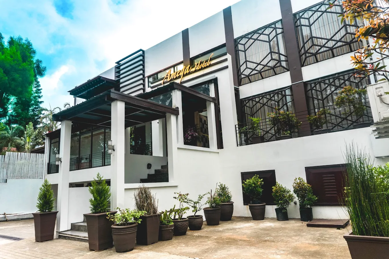 Amega Hotel in Tagaytay with modern facade, large windows, and potted plants lining the entrance.