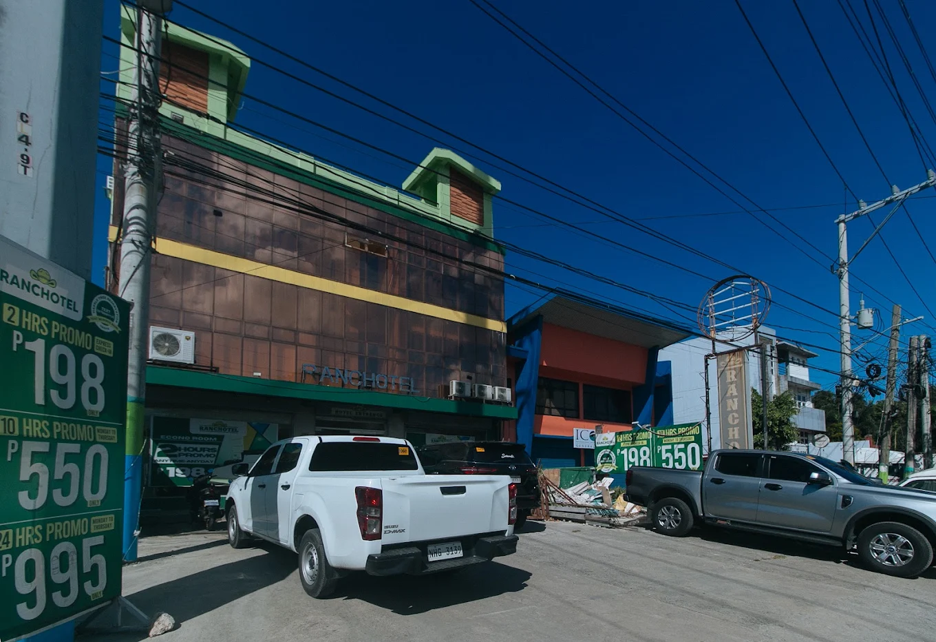 Ranchotel General Trias Cavite by RedDoorz exterior with parked vehicles and promotional signage under a clear blue sky.