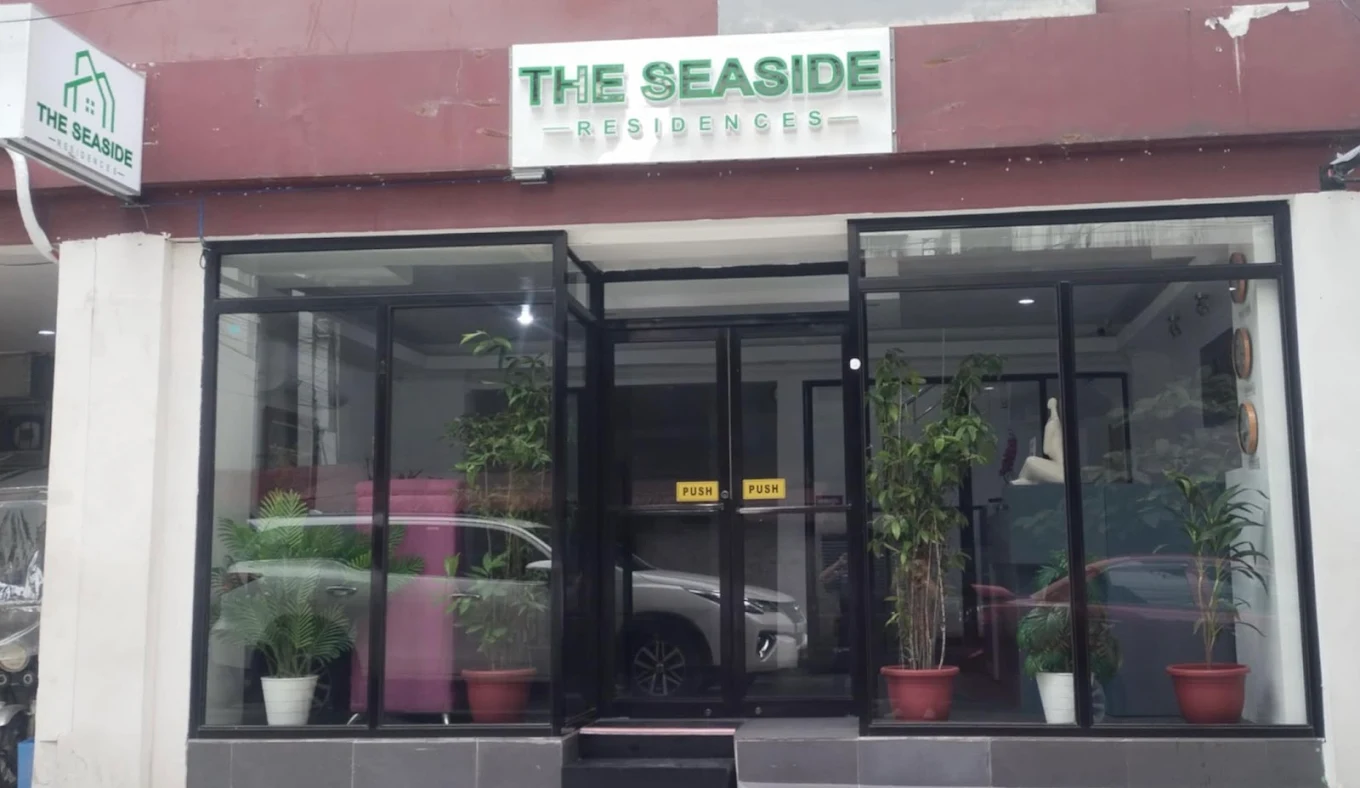 Entrance of Seaside Transient Guest House in Cavite City with glass doors and potted plants.