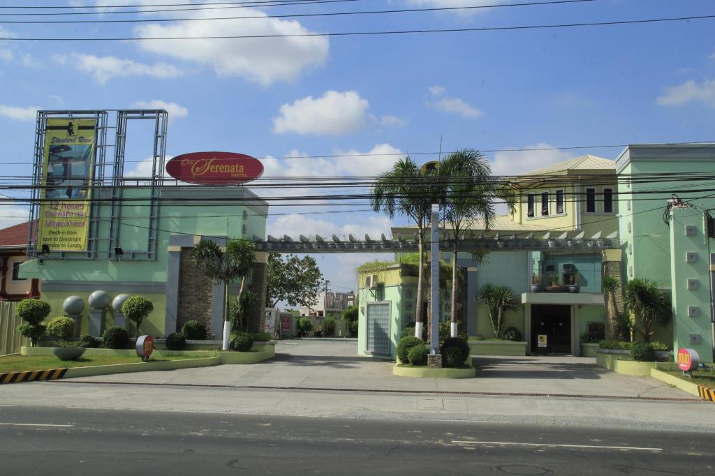 One Serenata Hotel entrance with green facade and palm trees in General Trias, Cavite under a clear blue sky.