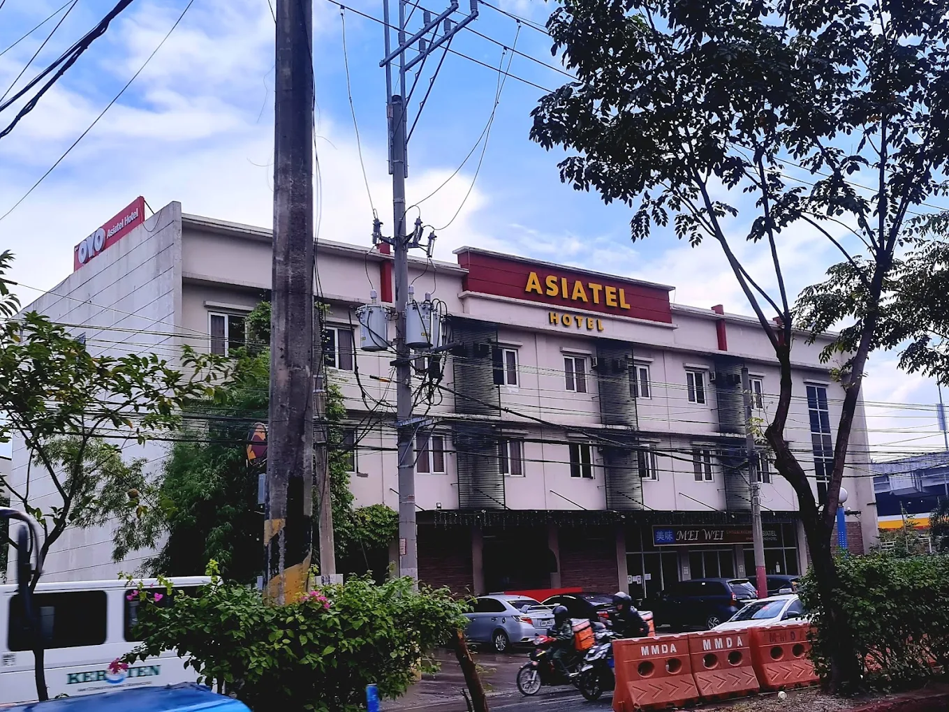 Asiatel Hotel in Bacoor, Cavite with parked cars and trees in the foreground.