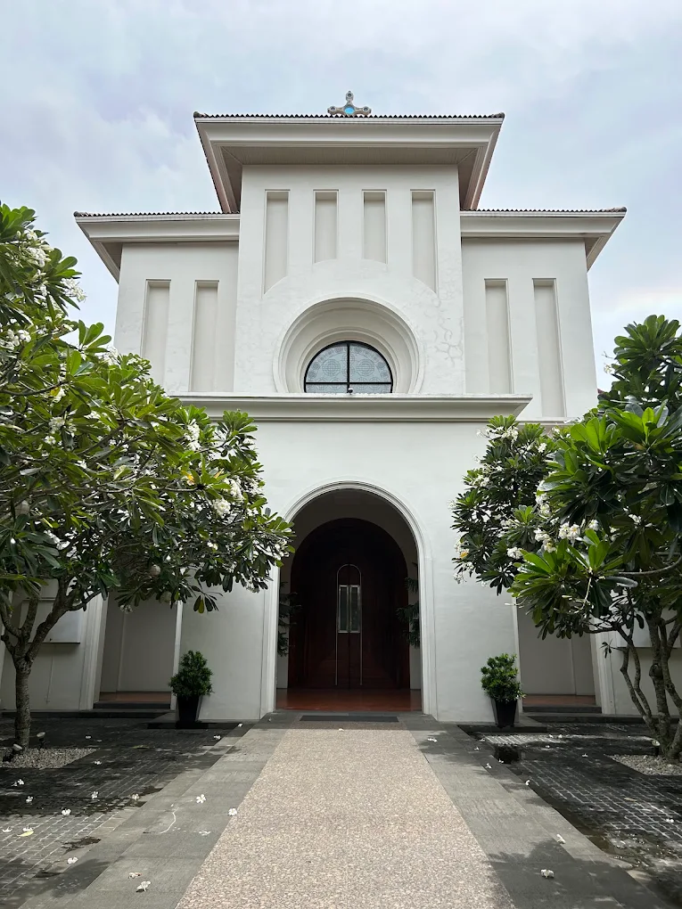 St. Benedict Parish in Silang, featuring a white facade, arched entrance, and surrounding greenery.