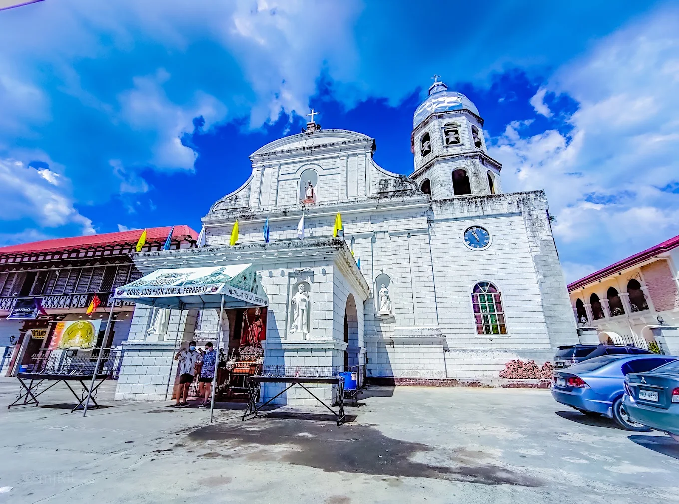 Diocesan Shrine of San Agustin in Tanza, featuring a historic church facade with statues and a clock tower under a blue sky.