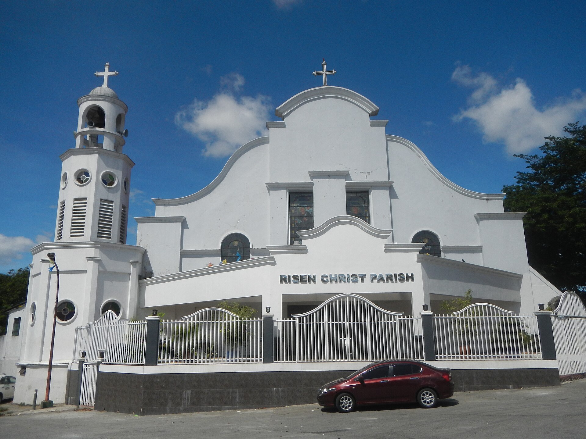 The Risen Christ Parish in Silang, Cavite with its white facade and bell tower under a clear blue sky.
