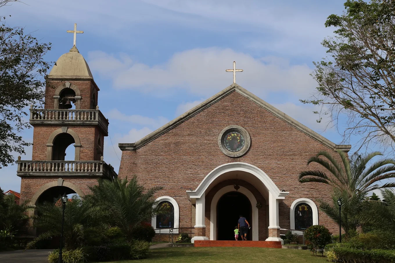 San Antonio de Padua Parish in Silang, featuring a brick facade, bell tower, and lush greenery under a blue sky.